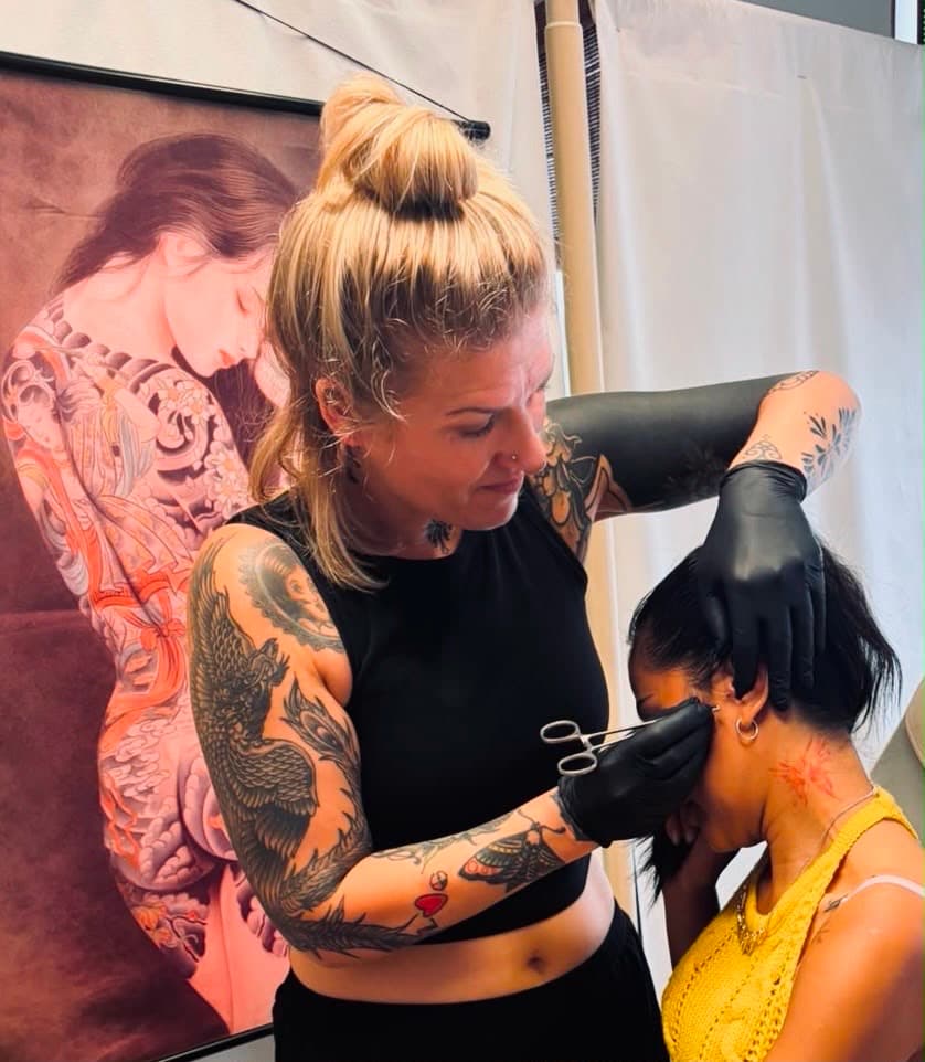 Liandra zet een piercing bij een klant in de studio